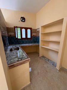 uma cozinha com um lavatório e prateleiras num quarto em sharika cafe home stay em Auroville