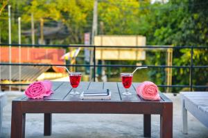 a wooden table with two wine glasses and pink roses at Relax - Budget Rooms in Batapola in Batapola