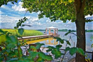 a dock with a gazebo on a lake at Panorama Hotel am Oberuckersee in Warnitz