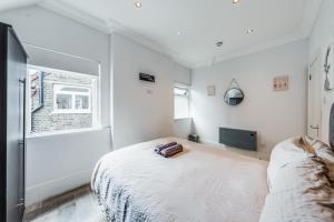 a white bedroom with a bed and a window at The Hideaway With AC in London