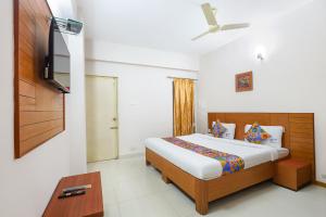 a bedroom with a bed and a flat screen tv at FabHotel RKH Skyline Residency in Chennai