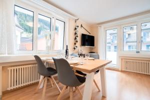 a dining room with a table and chairs and windows at Alpenheim Apartment in Andermatt