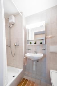 a white bathroom with a sink and a bath tub at Alpenheim Apartment in Andermatt
