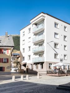 a white apartment building with benches in front of it at Alpenheim Apartment in Andermatt