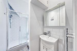 a white bathroom with a sink and a shower at The Hideaway With AC in London