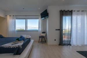 a bedroom with a bed and a large window at SunriseDreamHouse in Ponta Delgada