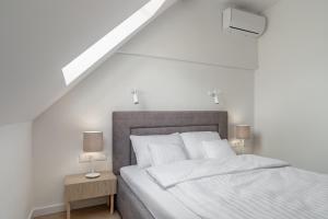 a white bedroom with a large bed with two lamps at Apartamenty SWAN in Gliwice