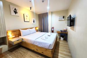 a hotel room with a bed and a television at DLT Suites Cebu powered by Cocotel in Minglanilla