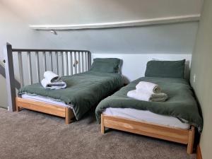 - 2 lits dans une chambre avec une couette verte dans l'établissement 19th-century fishermans cottage, à Corton