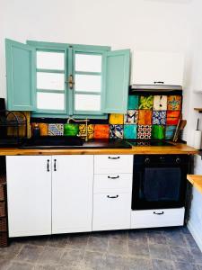 a kitchen with white cabinets and a black microwave at Villa Kastrouna, with private heated jacuzzi in Symi