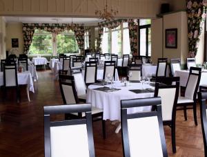 a dining room with white tables and chairs at Hotel Restaurant Le Lion Verd in Putanges