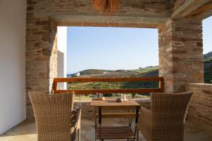 a table and chairs on a patio with a view at Spanos Apartments - Andros in Agios Petros