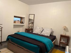 a bedroom with a bed with a blue blanket and a mirror at La Ruelle in Die