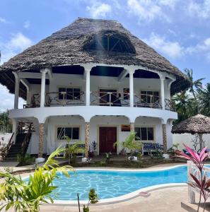 a villa with a swimming pool in front of it at Papa Romolo Villa's in Watamu