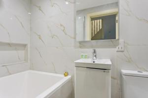 a white bathroom with a sink and a mirror at Charming Windsor Cottage, Castle Views, Garden & Walk Everywhere in Windsor +18 photos