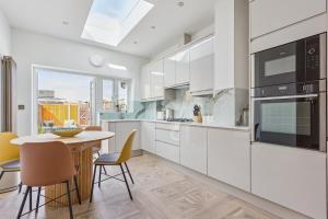 a kitchen with white cabinets and a table and chairs at Charming Windsor Cottage, Castle Views, Garden & Walk Everywhere in Windsor