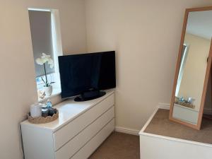 a tv on top of a dresser with a mirror at Modern homestay in Wolverhampton in Bushbury