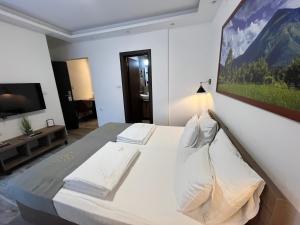 a bedroom with a large white bed with a painting on the wall at Soko IN Spa in Soko Banja