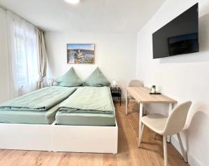 a white bedroom with a bed and a table at Privatzimmer in Apartment Brunnenstraße Braubach in Braubach
