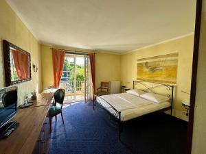 a bedroom with a bed and a desk and a window at Hotel Landhaus Milser in Duisburg