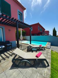 a swimming pool with two loungers next to a house at Sunset Dreams - Arco da Calheta in Arco da Calheta