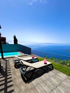 two lounge chairs sitting next to a swimming pool at Sunset Dreams - Arco da Calheta in Arco da Calheta