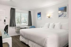 a white bedroom with a large bed and a window at SureStay Hotel by Best Western Rossland Red Mountain in Rossland