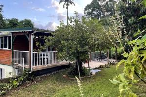 a house with a porch and a tree at Appartement spacieux à Sainte-Rose, 70 m² avec jardin in Sainte-Rose