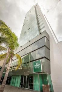 a building with a palm tree in front of it at Suíte em Hotel de Luxo Bourbon in Belo Horizonte