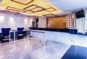 a bar in a room with blue chairs at Suíte em Hotel de Luxo Bourbon in Belo Horizonte