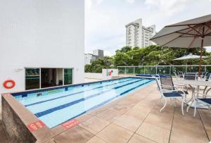 a swimming pool with a table and chairs and an umbrella at Suíte em Hotel de Luxo Bourbon in Belo Horizonte