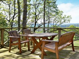 a wooden table and chairs on a deck with a view at 4 person holiday home in Slöinge in Ugglarp