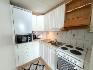 a kitchen with white cabinets and a sink and a stove at Cozy city suites in Rovaniemi