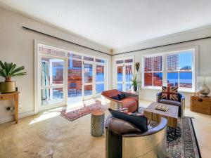 a living room with chairs and tables and windows at Trendy home in heart of City Heritage, Mtn Views in Cape Town