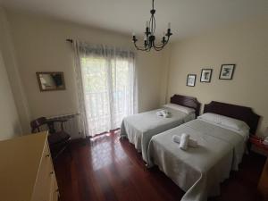 a bedroom with two beds and a chandelier at Balcón del Cantábrico in Comillas +25 photos