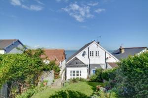 una casa blanca con el océano al fondo en Umballa, en Herne Bay