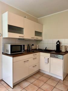 a kitchen with white cabinets and a microwave at Haases Ferienwohnung in Remscheid