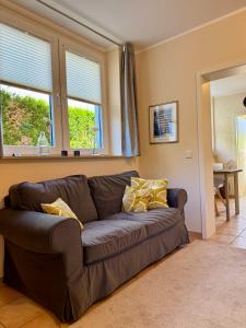 a brown couch in a living room with two windows at Haases Ferienwohnung in Remscheid