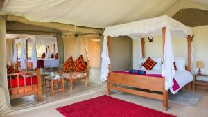 a bedroom with a tent with a bed and chairs at Mara Sidain safaris in Sekenani +59 photos