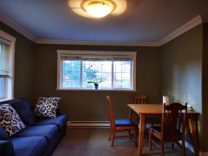 a living room with a blue couch and a table and a window at Eagle's Guest Suits in Victoria +9 photos