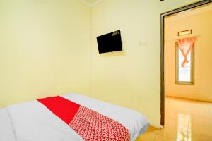 a bedroom with a red and white blanket on a bed at OYO 94716 Hartini Residence Syariah in Depok