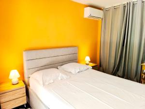 a bedroom with a bed with yellow walls and two lamps at Le Soa - piscine - jardin - parking - clim - wifi in Saint-Gilles-les-Bains