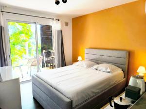 a bedroom with a large bed and a balcony at Le Soa - piscine - jardin - parking - clim - wifi in Saint-Gilles-les-Bains