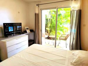 a bedroom with a bed and a sliding glass door to a patio at Le Soa - Studio - Jardin - Piscine in Saint-Gilles les Bains +2 photos