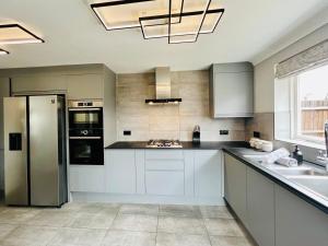a kitchen with white cabinets and a stainless steel refrigerator at Poppies in Colchester