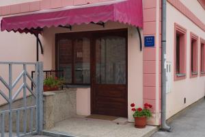 ein rosafarbenes Gebäude mit einer Tür und einem rosa Regenschirm in der Unterkunft Apartment Pokos in Varaždinske Toplice