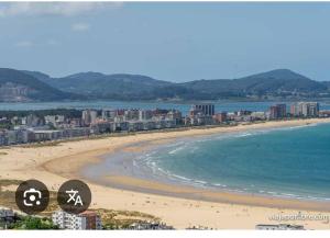 a view of a beach with buildings and the ocean at Apartamento Aurora cerca de Laredo y Santoña y Piscina Comunitaria in Bádames