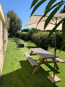 un tavolo da picnic e un ombrellone sull'erba di Maison avec jardin privé à Plaisance-du-Touch a Plaisance-du-Touch