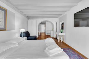 a white bedroom with a white bed and a blue chair at The house of Ripa di porta ticinese 13 in Milan