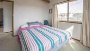 a bedroom with a bed and a large window at Summer House On Kurrawa - stunning beach views in Kioloa